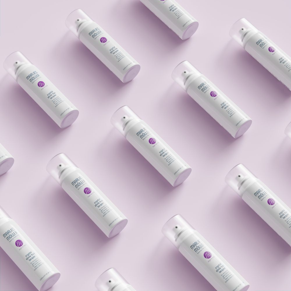 Meerdere witte haarsprays van Marlies Möller op roze achtergrond. Opschrift: Crystal Shine Hair Lacquer.