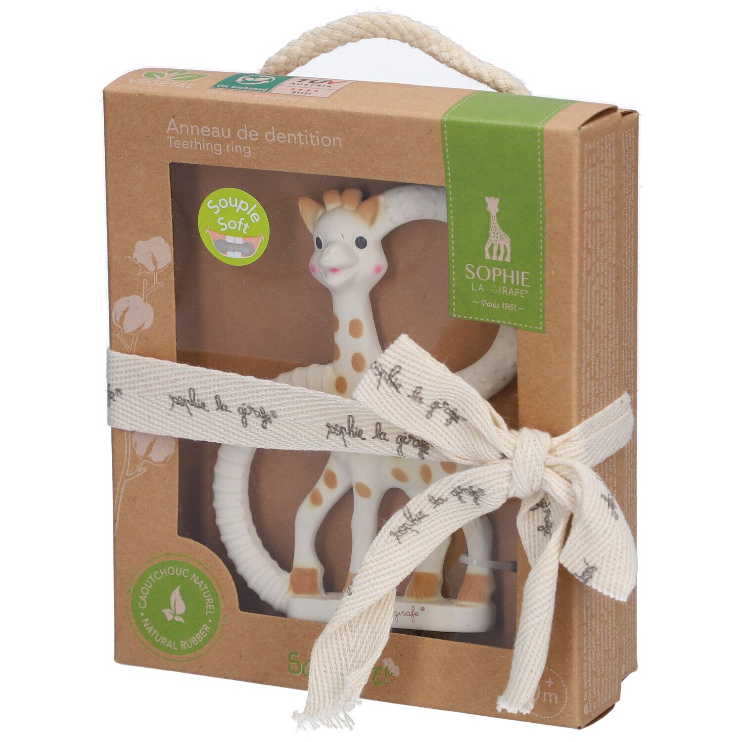 Bijtring in doos. Giraffe vorm, beige met bruine vlekken. Lint met tekst. Transparant venster.