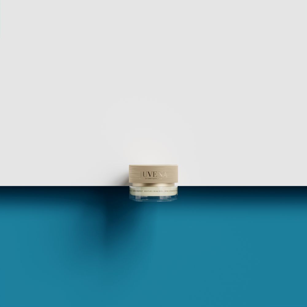 Petit pot de crème avec couvercle doré. Inscription : Juvena. Sur fond bleu et blanc.