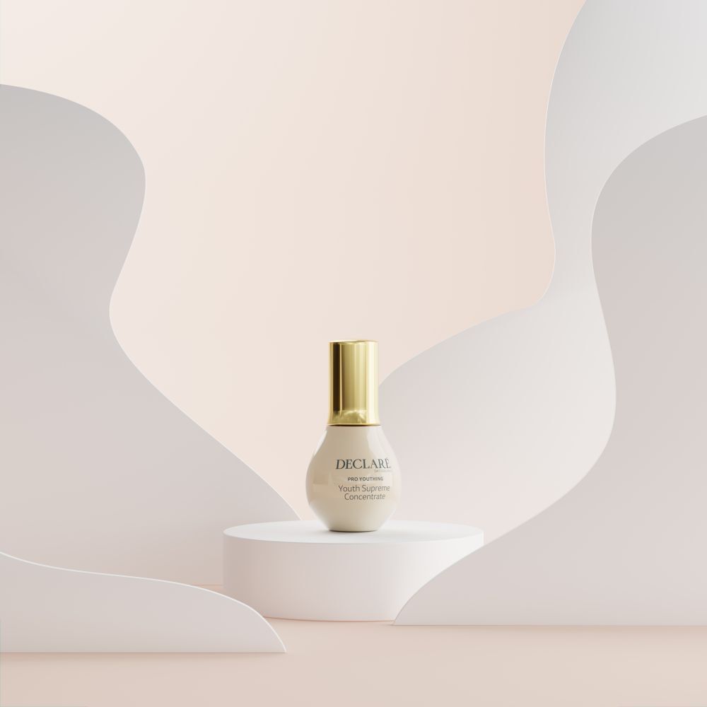 Flacon beige à bouchon doré sur socle blanc. Fond : formes abstraites beiges.