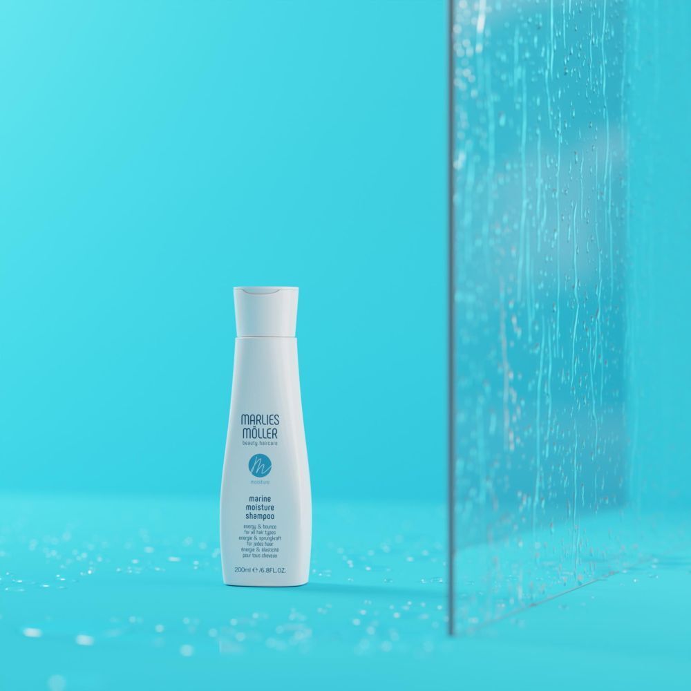 Shampoo fles op blauwe achtergrond en glas. Opschrift: Marlies Möller, Marine Moisture Shampoo.