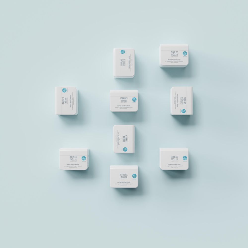 Meerdere witte potten op blauwe achtergrond. Marlies Möller Marine Moisture Mask.