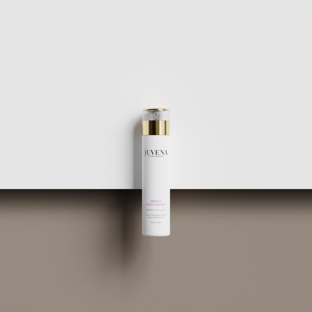 Flacon blanc avec bouchon doré. Inscription: Juvena, Miracle Boost Essence. Sur fond blanc.