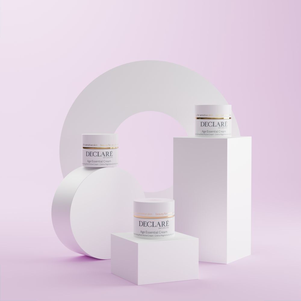 Drie witte sokkels met potten. DECLARÉ-logo en productnaam Age Essential Cream. Geometrische achtergrond.