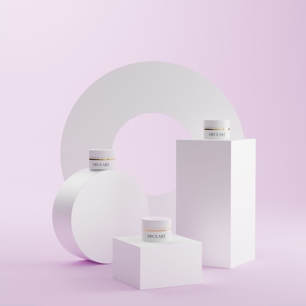 Plusieurs socles blancs avec des pots blancs. Fond avec des formes géométriques. Logo DECLARÉ visible.