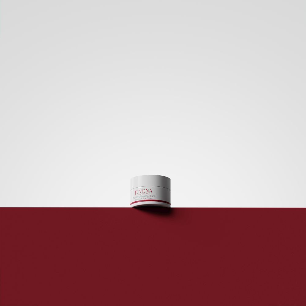 Pot de crème sur fond rouge et blanc. Inscription: JUVENA, REJUVEN® Superior Care. Couvercle blanc, bande rouge.