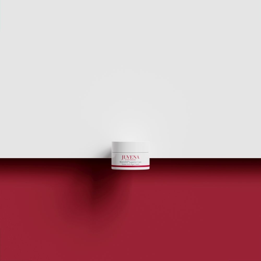 Pot de crème sur fond rouge et blanc. Inscription: JUVENA, REJUVEN® Superior Care. Couvercle blanc, bande rouge.