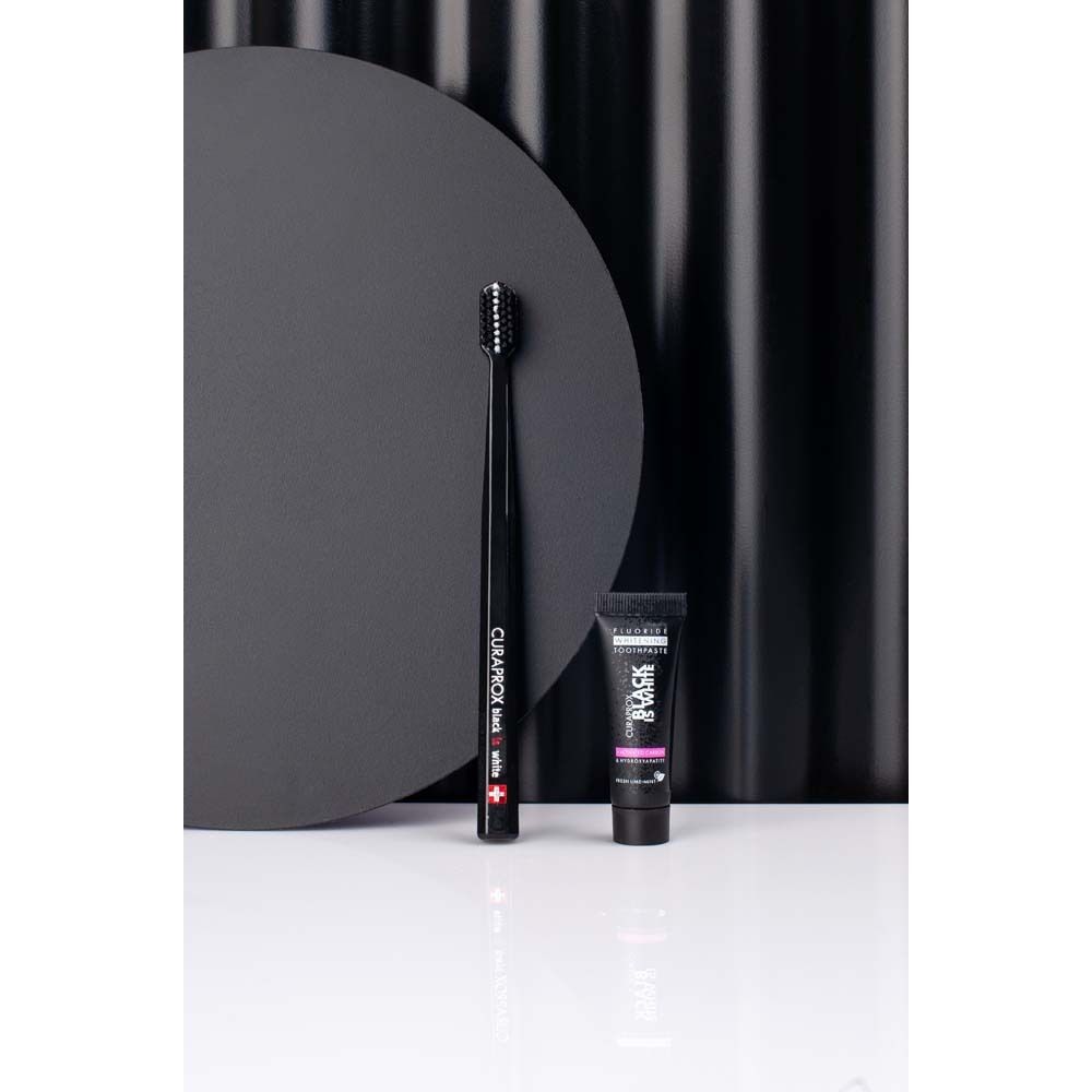 CURAPROX Black is White Light-Pack. Zwarte tandenborstel en tandpasta. Achtergrond met cirkels. Merk zichtbaar.