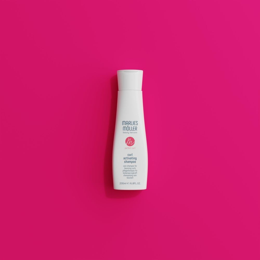 Marlies Möller shampoo fles op roze achtergrond. Productnaam en logo zichtbaar.