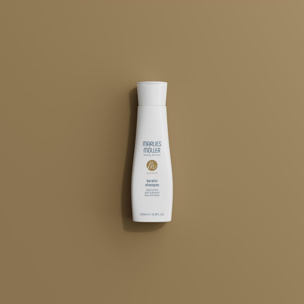 Flacon de shampooing Marlies Möller Keratin sur fond beige. Flacon avec bouchon blanc et étiquette.
