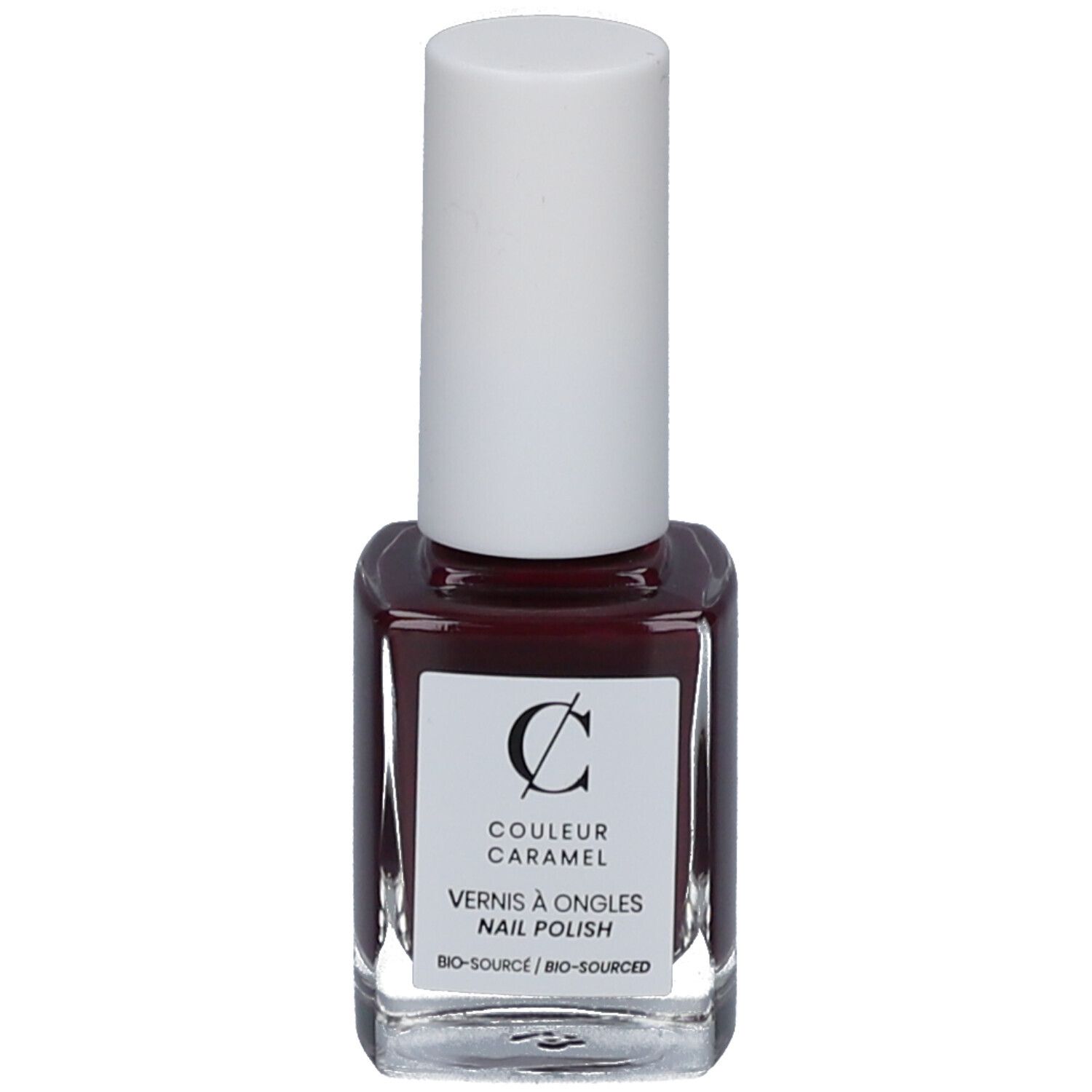 Nagellakfles met witte dop. Etiket met logo en tekst 'COULEUR CARAMEL'. Donkerrode nagellak.