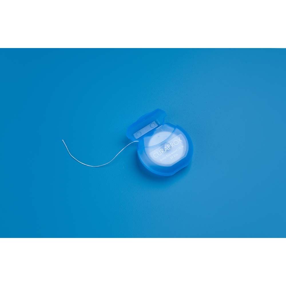 Blauwe tandenpoetsdraad met uitgetrokken draad. Op blauwe achtergrond.