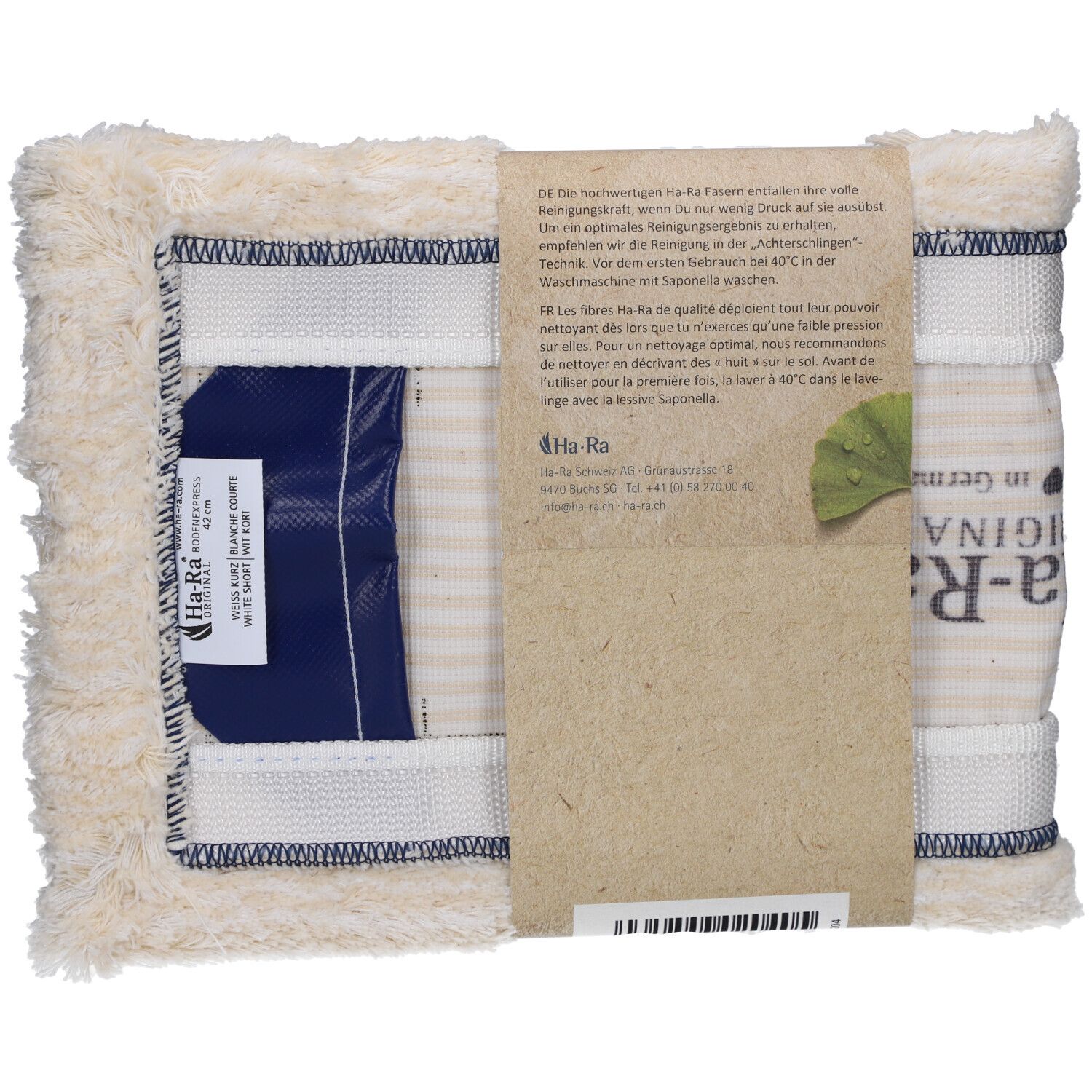 Vloervezel, wit, kort. Rechthoekige vezel met blauwe sluiting. Papieren band met tekst en logo. "Ha-Ra" logo zichtbaar.