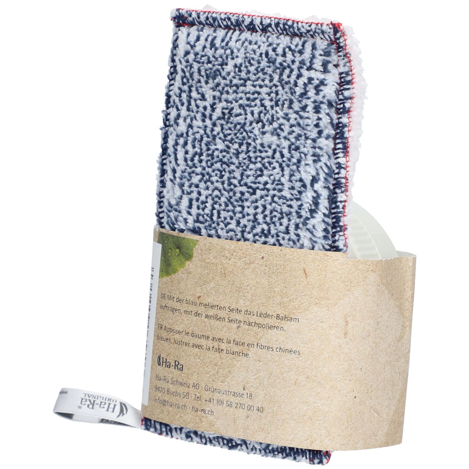 Verzorgingsdoek met lederbalsemverpakking. Doek met blauw-wit patroon en rode rand. Verpakking van bruin papier. Tekst op de verpakking.