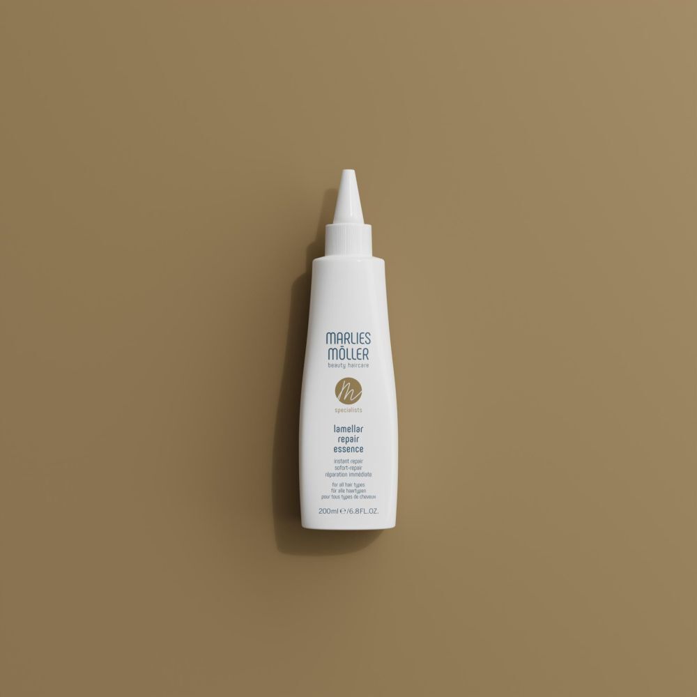 Witte fles met punt, Marlies Möller, Lamellar Repair Essence, op bruine achtergrond. Bovenaanzicht.