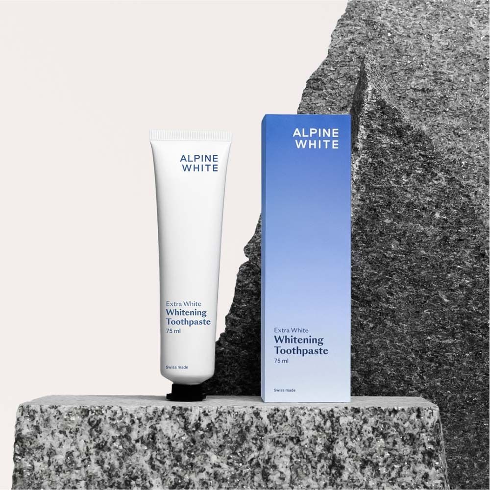 Tube et boîte de dentifrice sur une pierre. Inscription : ALPINE WHITE, Extra White Whitening Toothpaste.