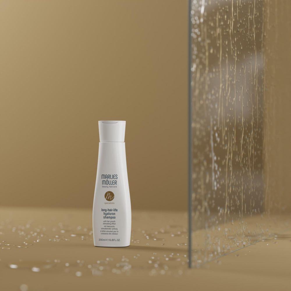 Flacon de shampooing blanc avec bouchon blanc. Inscription: Marlies Möller, Lang-Haar-Life Hyaluron Shampoo. Fond: paroi vitrée.