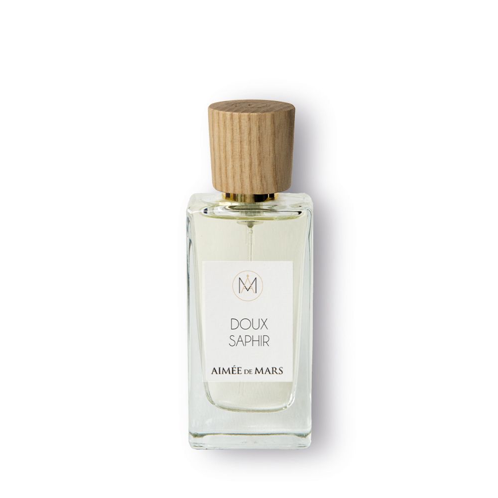 Flacon de parfum avec bouchon en bois. L'étiquette indique "Doux Saphir" et "Aimée de Mars".