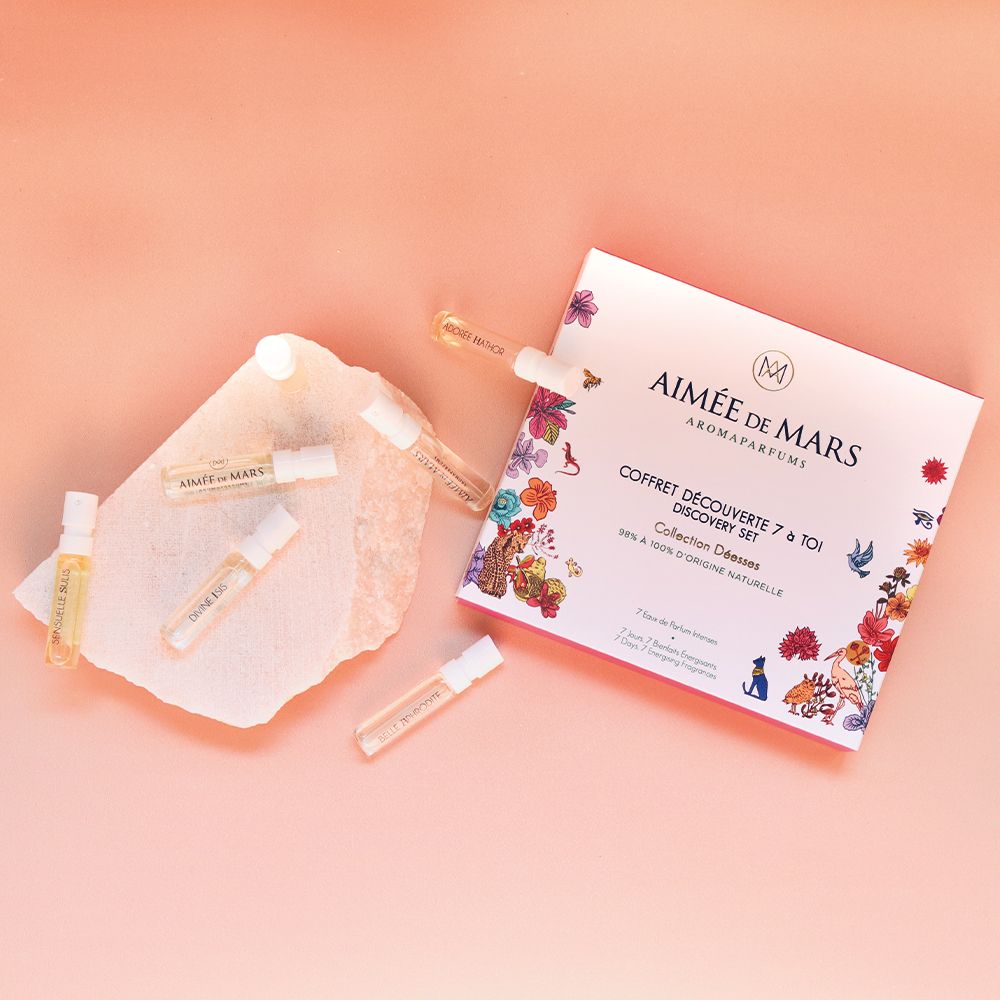 Parfummonsters op een steen. Geschenkdoos op de achtergrond. Roze achtergrond. Verschillende kleine glazen flesjes.