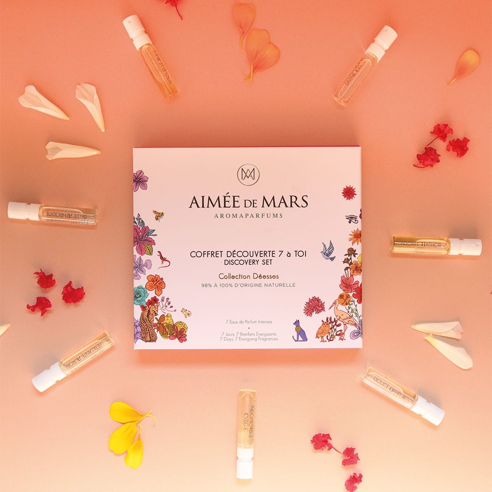 Parfummonsters en bloemblaadjes op roze achtergrond. Geschenkdoos in het midden. Verschillende kleine glazen flesjes.