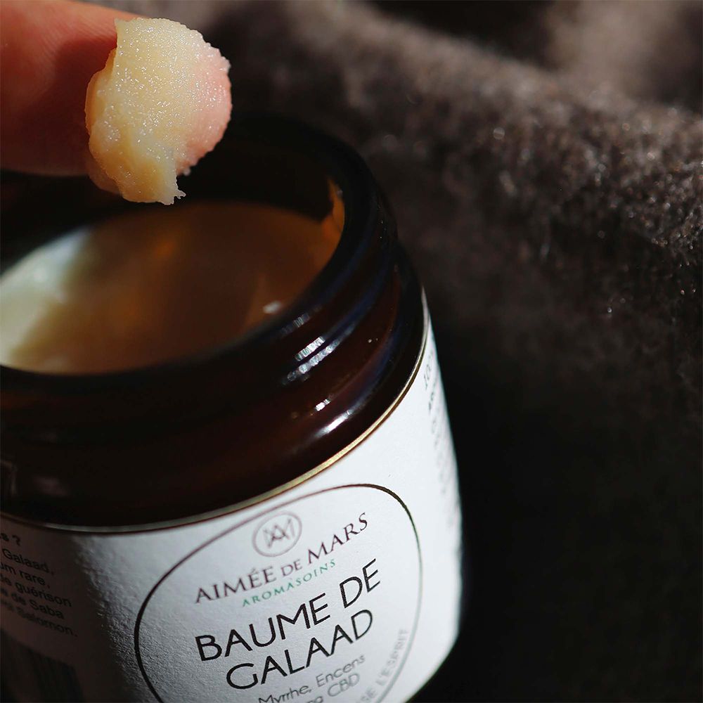 Close-up van een vinger met balsem. De balsem is licht en romig. De achtergrond is wazig.