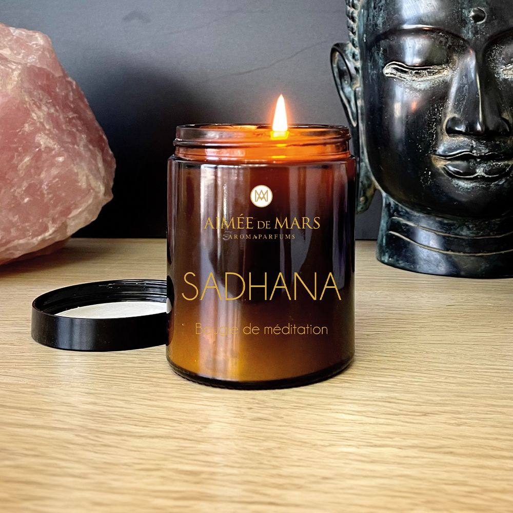 Brandende bruine kaars met zwarte deksel. Opschrift: AIMÉE DE MARS, SADHANA, Bougie de méditation.