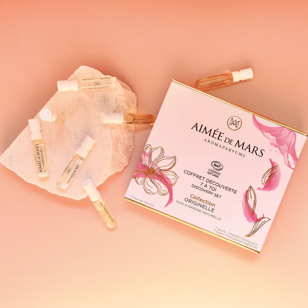 Aimée de Mars® Discovery Set Collection. Une boîte et sept petits flacons sur fond rose. Pétales.