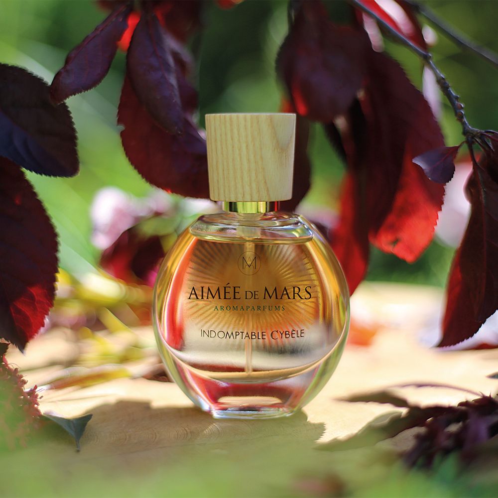 Ronde glazen fles met houten dop. Opschrift: Aimée de Mars, Indomptable Cybèle. Aromaparfum.