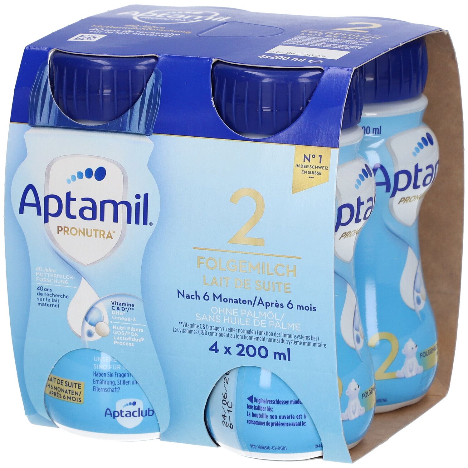 Emballage de quatre bouteilles Aptamil 2 Lait de suite. Bouteilles bleues avec bouchons bleus, dans un emballage en carton. Inscriptions : Aptamil, 2, Lait de suite.