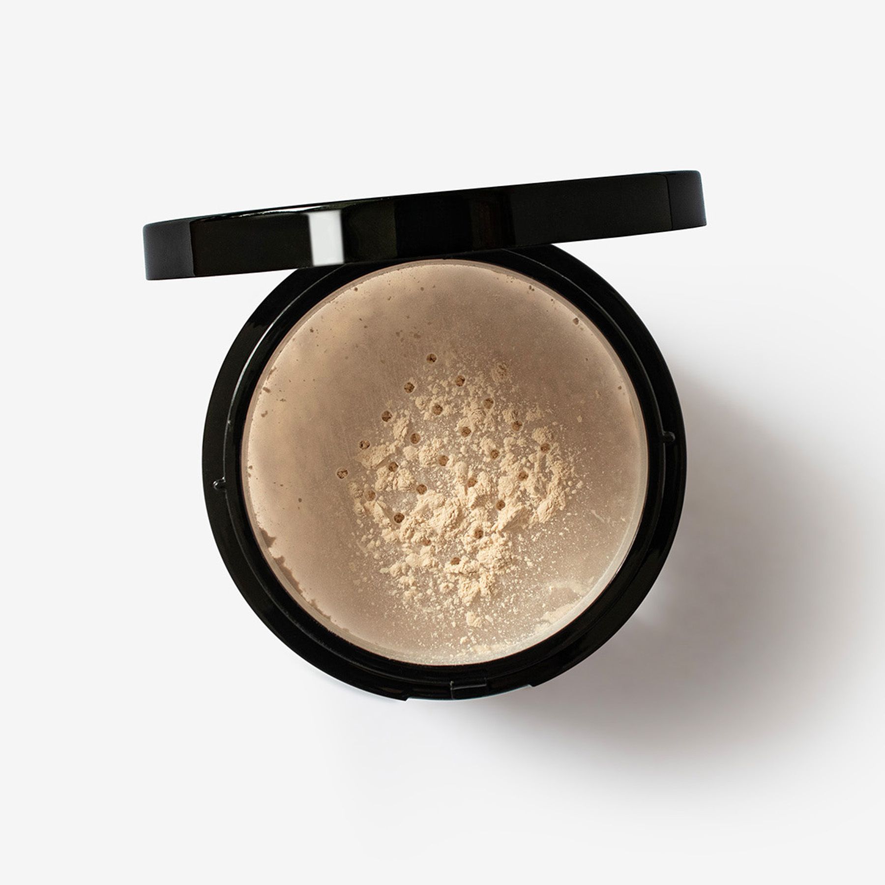 Boîte de poudre avec couvercle noir. Poudre visible. Fond blanc.