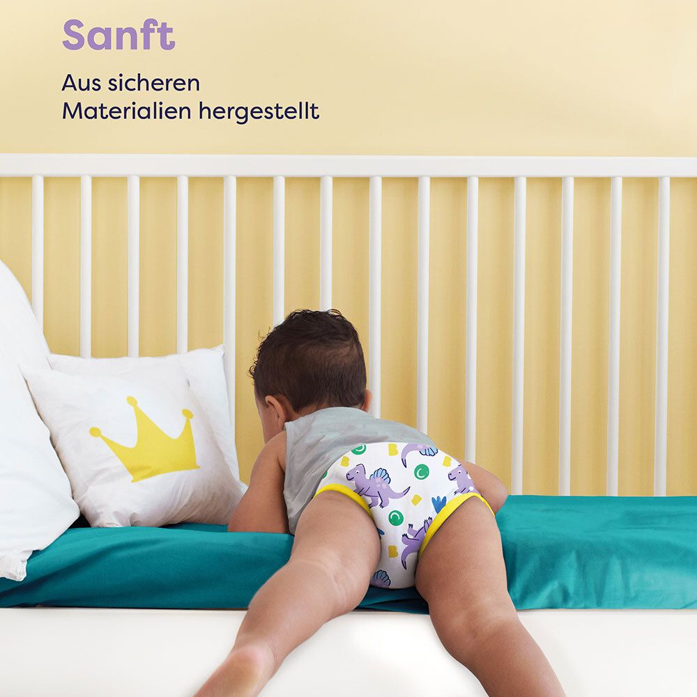 Enfant avec culotte d'apprentissage sur le lit. Texte: Doux. Fabriqué avec des matériaux sûrs.
