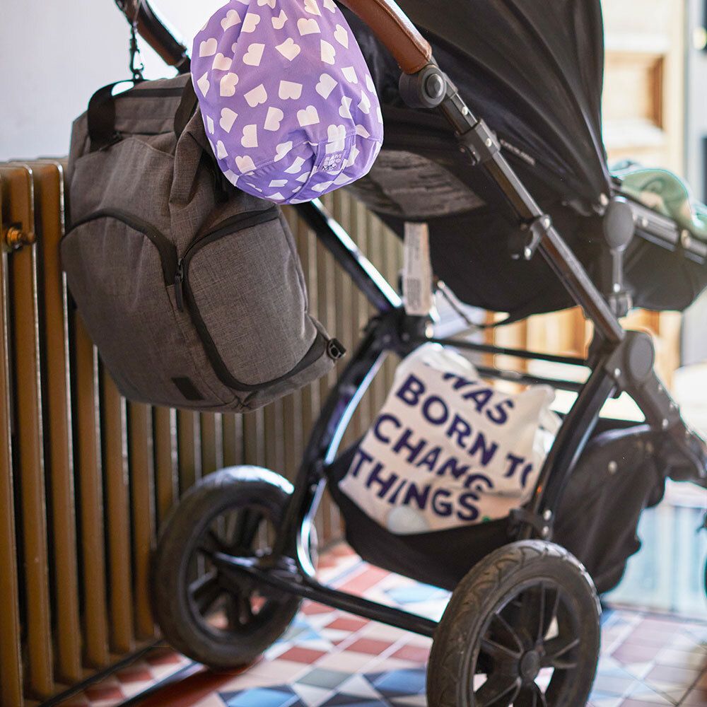 Paarse tas met witte wolkenpatroon, bevestigd aan een kinderwagen.