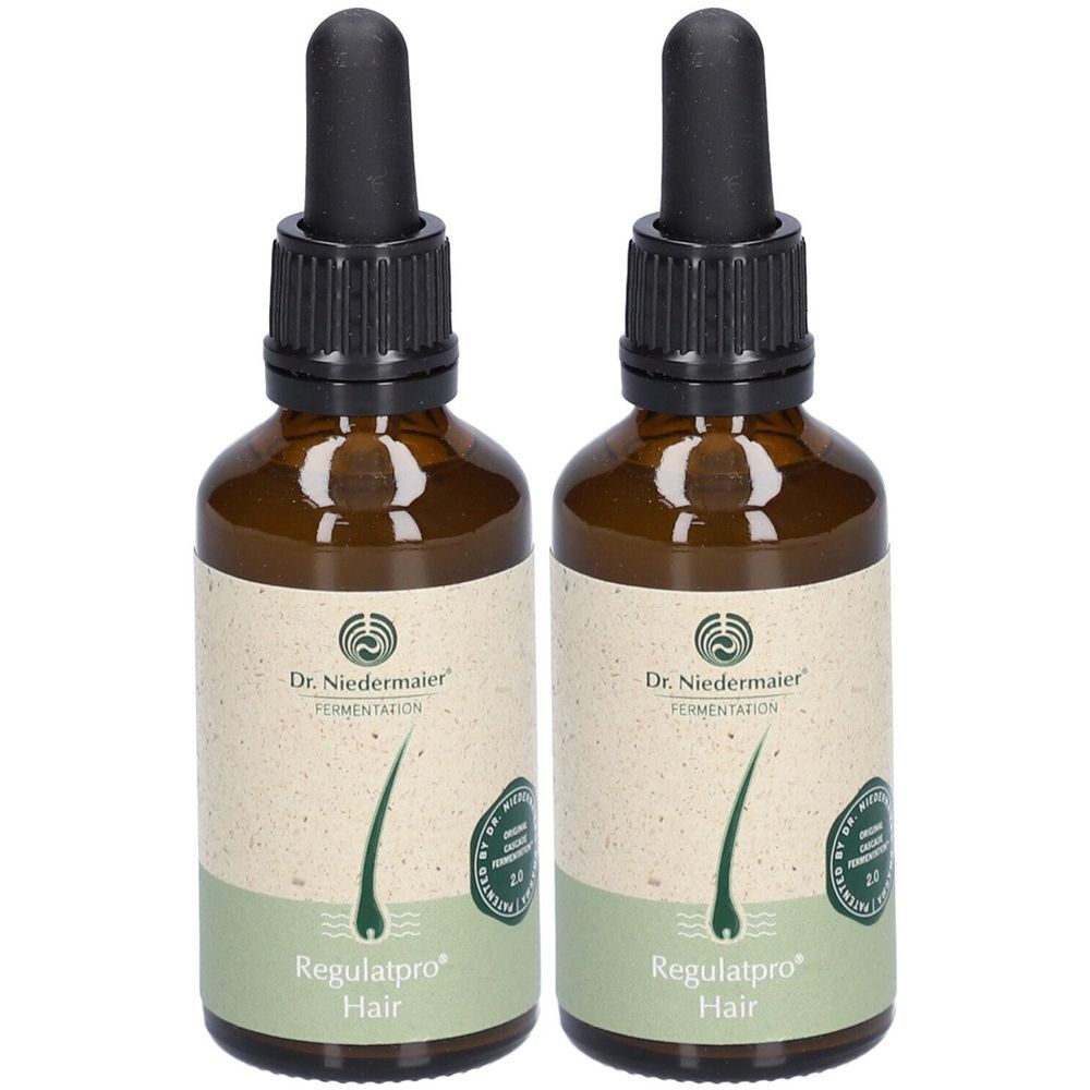Deux flacons en verre brun avec pipettes noires. Étiquettes avec le texte «Regulatpro Hair». Logo Dr. Niedermaier.