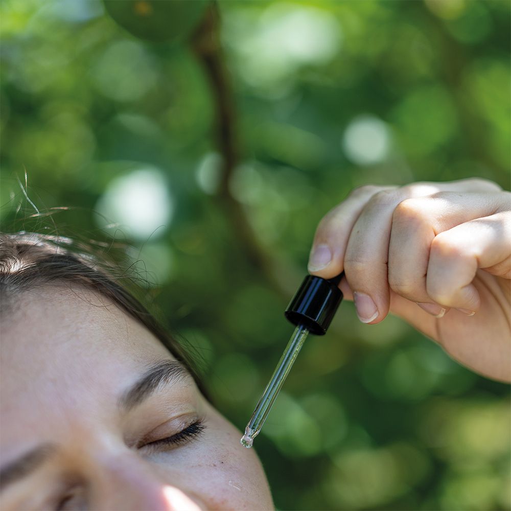 Close-up van een gezicht. Pipet druppelt serum op de huid.