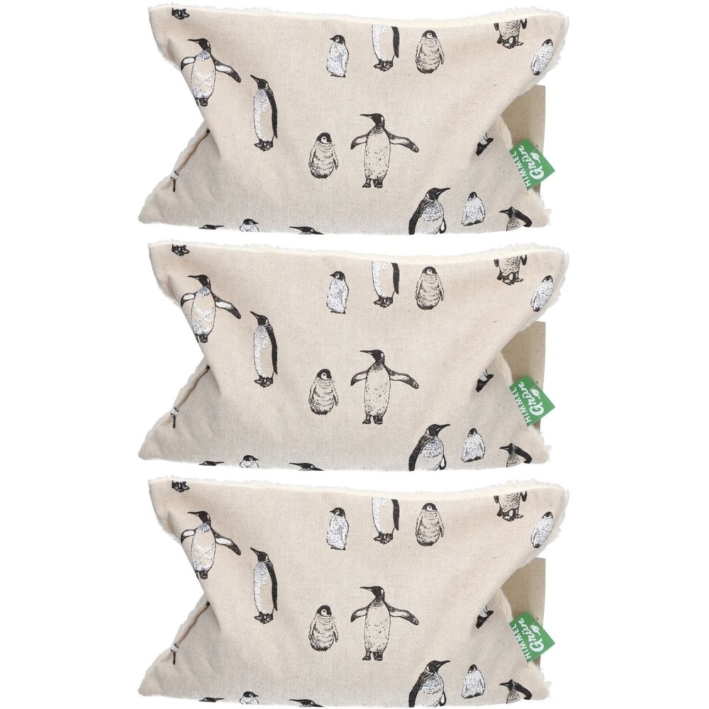 Trois coussins aux noyaux de cerises avec motif pingouin. Tissu beige avec illustrations de pingouins noirs. Étiquettes vertes et blanches.