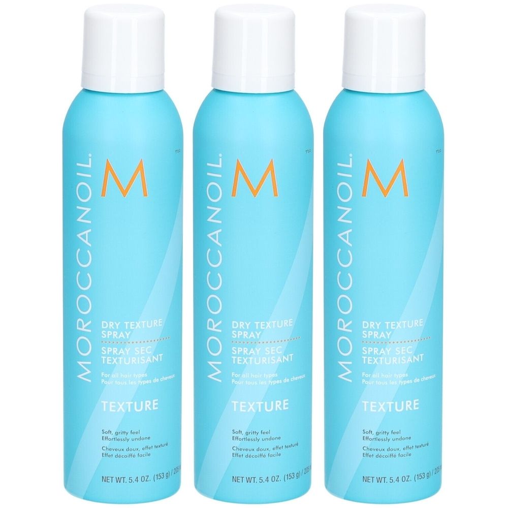 Trois flacons de spray texturisant sec Moroccanoil bleus avec bouchons blancs. Logo et nom du produit visibles.