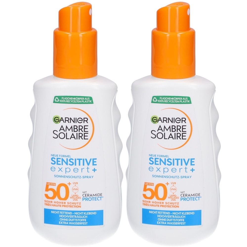 Deux flacons de Garnier Ambre Solaire Sensitive Expert+ Spray solaire SPF50+. Flacons blancs avec vaporisateurs orange.
