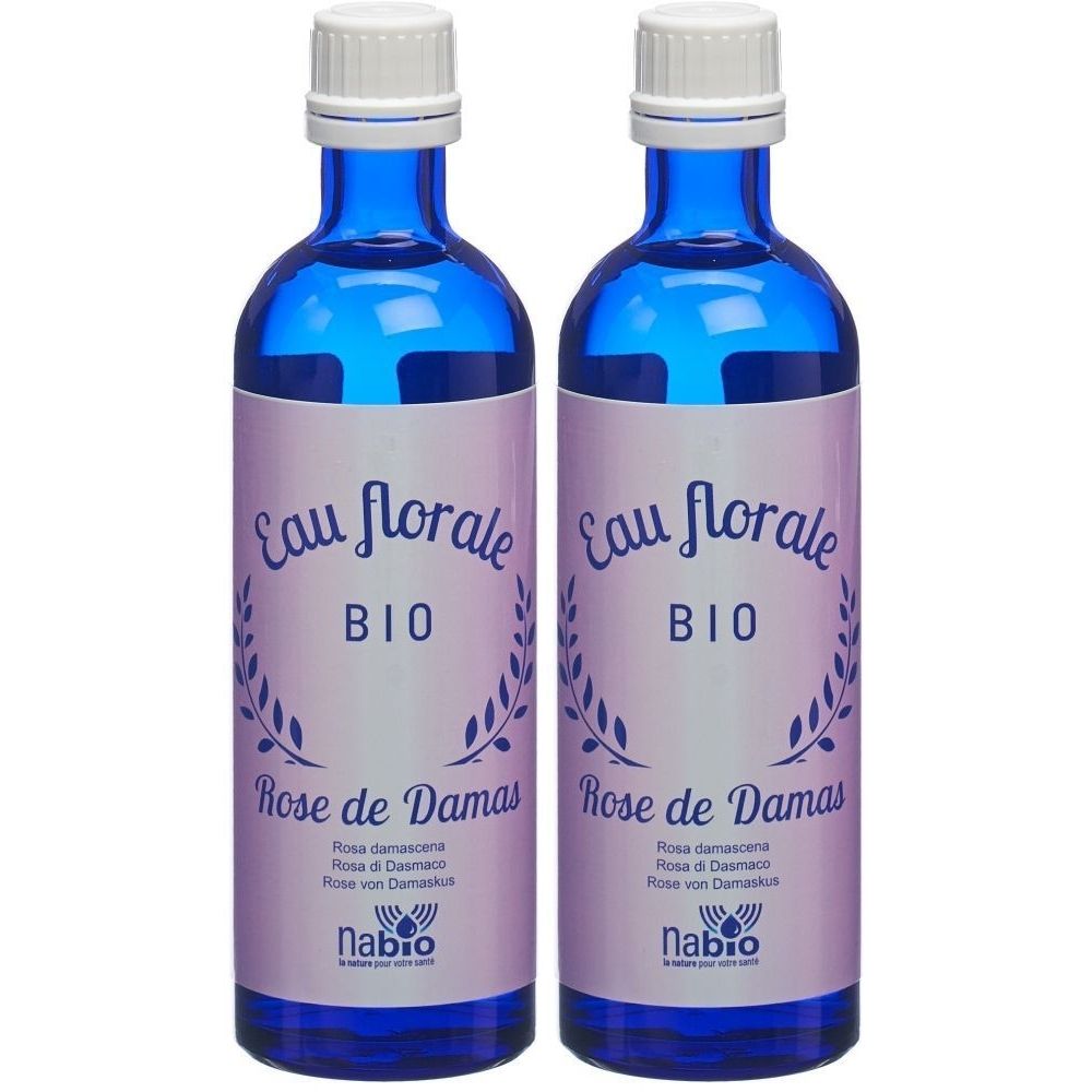 Twee blauwe glazen flessen met witte dop. Etiket met "Eau florale BIO Rose de Damas" en logo. Merk: Nabio.