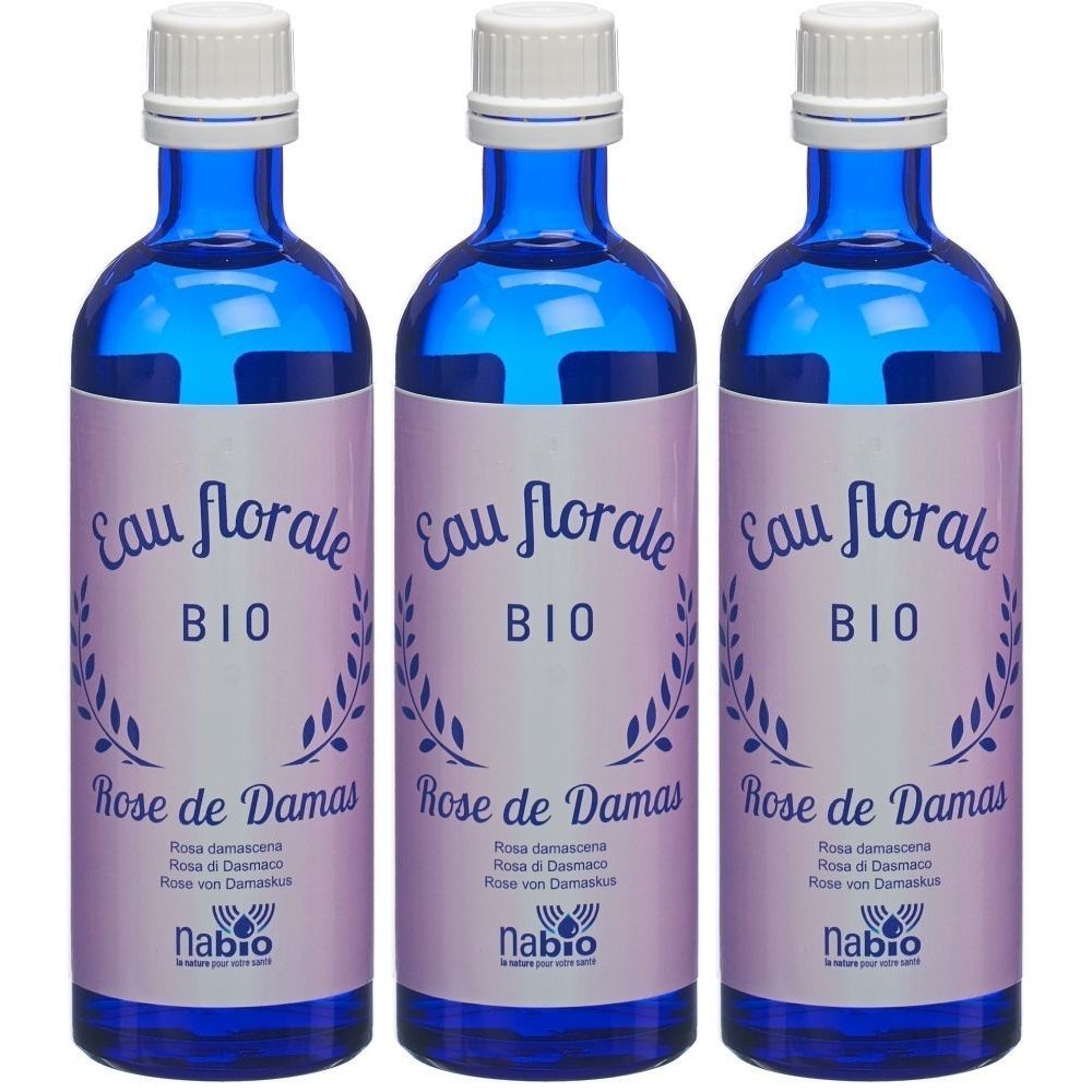 Drie blauwe glazen flessen met witte dop. Etiket met "Eau florale BIO Rose de Damas" en "nabio" logo.