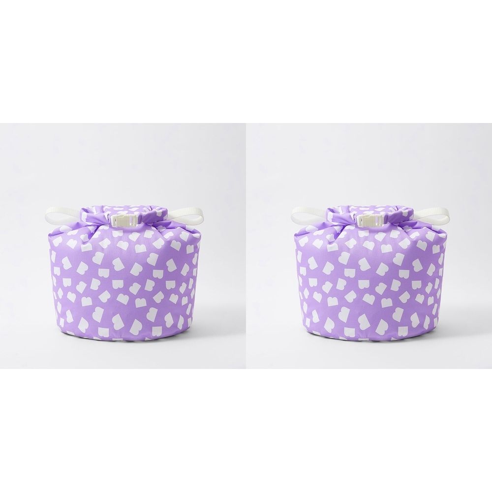 Sac à langer rond violet à motifs blancs. Fermeture supérieure avec cordon blanc. Deux sacs côte à côte.