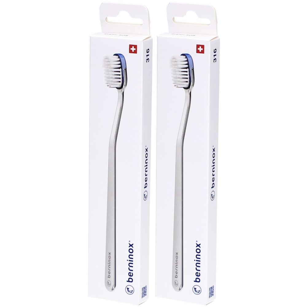 Twee tandenborstels in witte verpakkingen. Zichtbaar zijn de borstelkoppen met blauwe borstelharen en zilverkleurige handvatten. Verpakking met Zwitsers kruis.