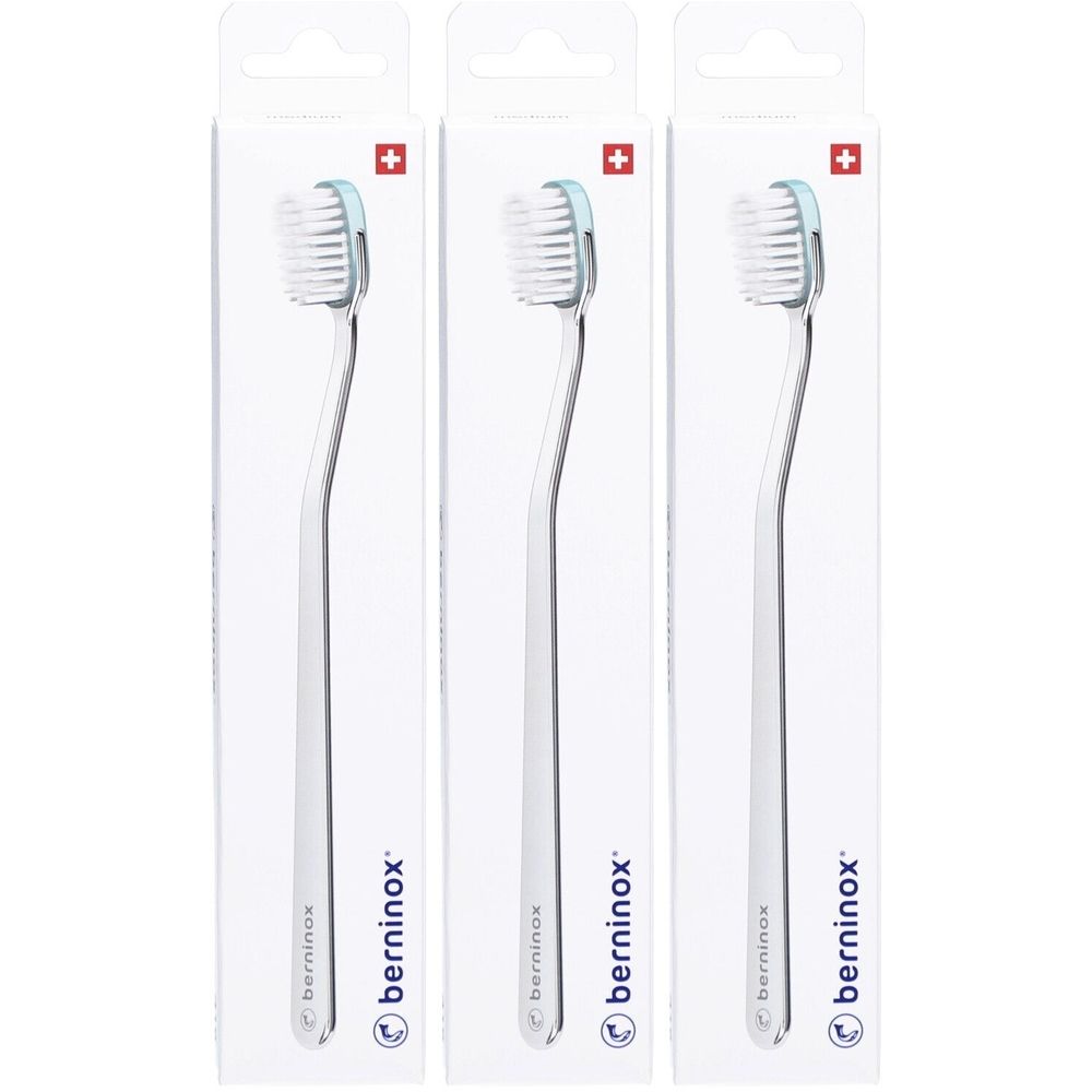 Drie tandenborstels in verpakking. Witte borstelharen, lichtblauwe kop, transparante steel. Merk: berninox. Zwitsers kruis.
