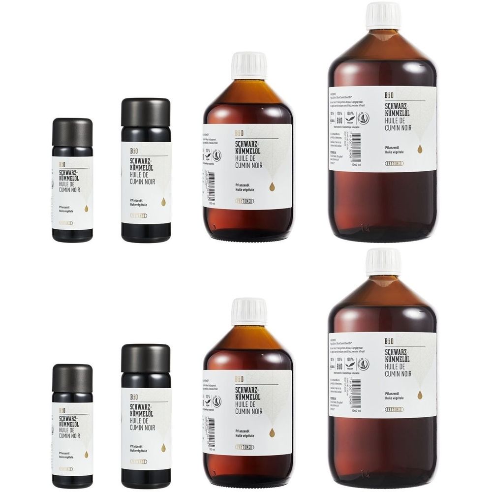 Verschillende flessen en kleine flesjes met etiketten. Opschrift: BIO Zwarte komijnolie, Huile de cumin noir.