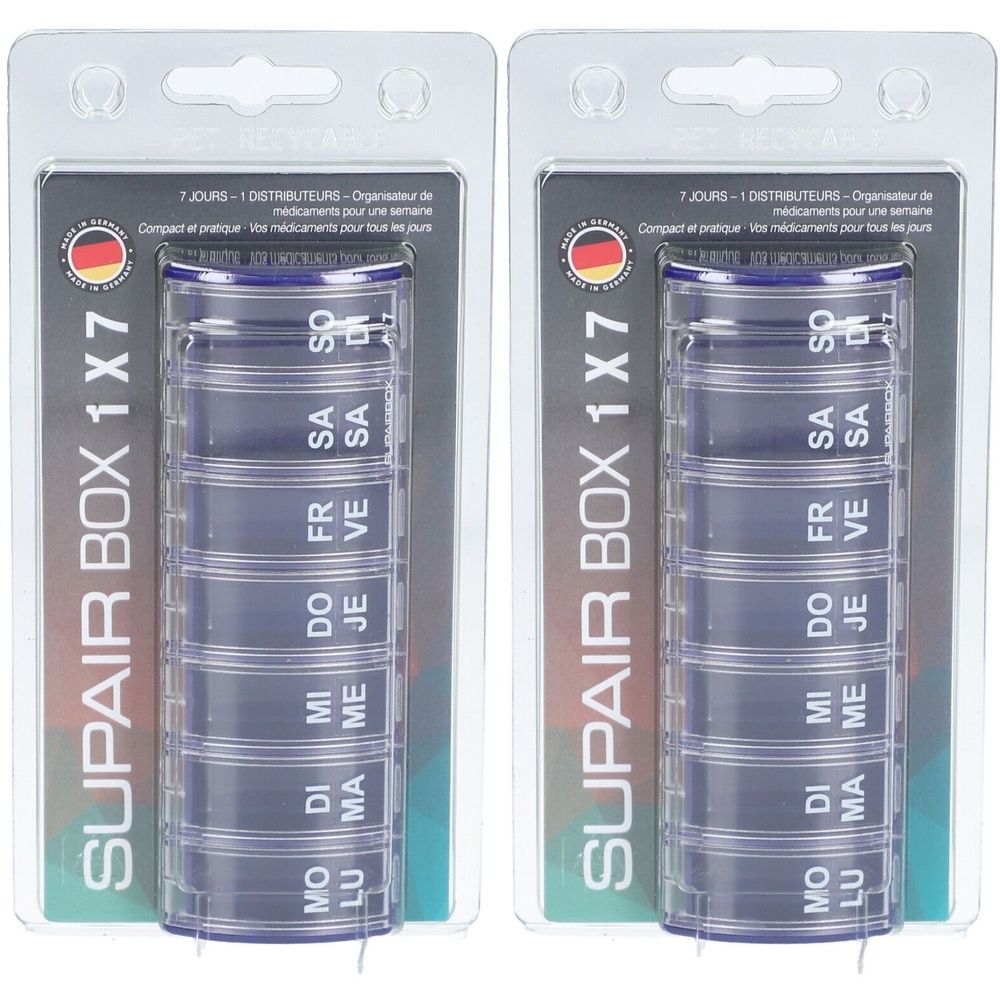 Twee verpakkingen SUPAIR BOX 1x7, wekelijkse pillendoosjes. Blauwe, cilindrische containers met zeven compartimenten, gelabeld met dagen.