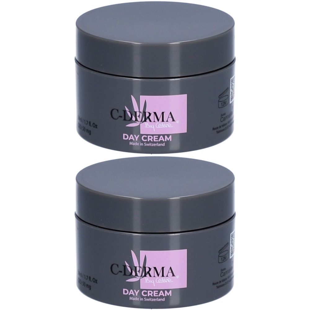 Deux pots de C-DERMA Day Cream. Couvercles gris, étiquette rose avec texte. Fabriqué en Suisse.
