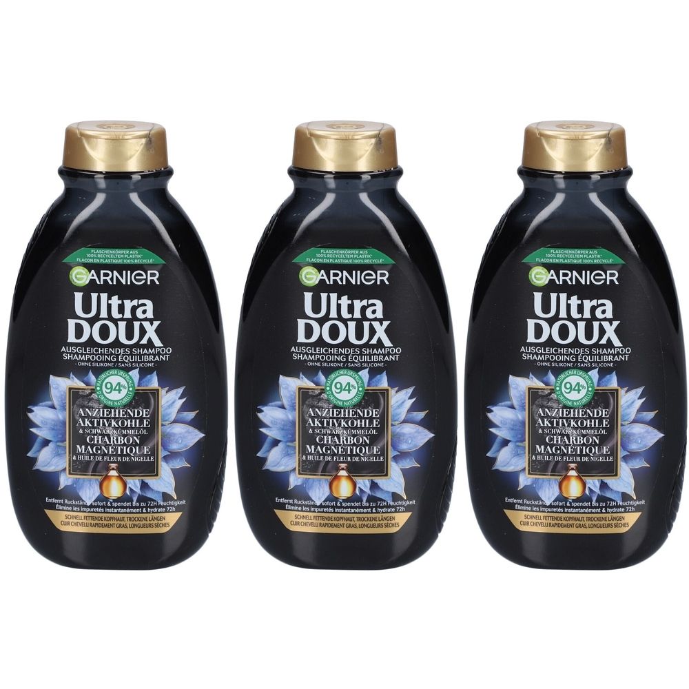 Drie zwarte shampoo flessen met gouden doppen. Opschrift: Garnier Ultra Doux, Magnetische Houtskool.