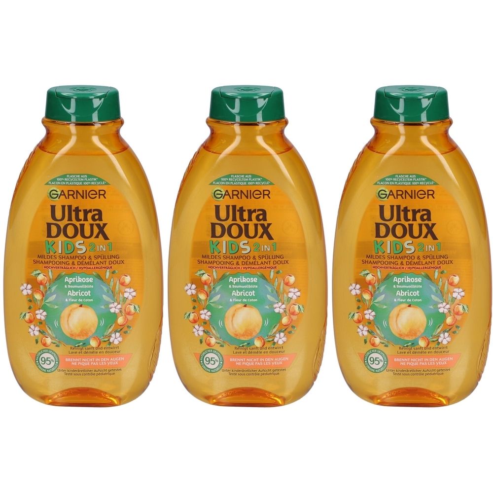 Drie flessen Garnier Ultra Doux Kids 2 in 1 shampoo. Oranje flessen met groene dop. Opschrift: Aprikose, Abricot.