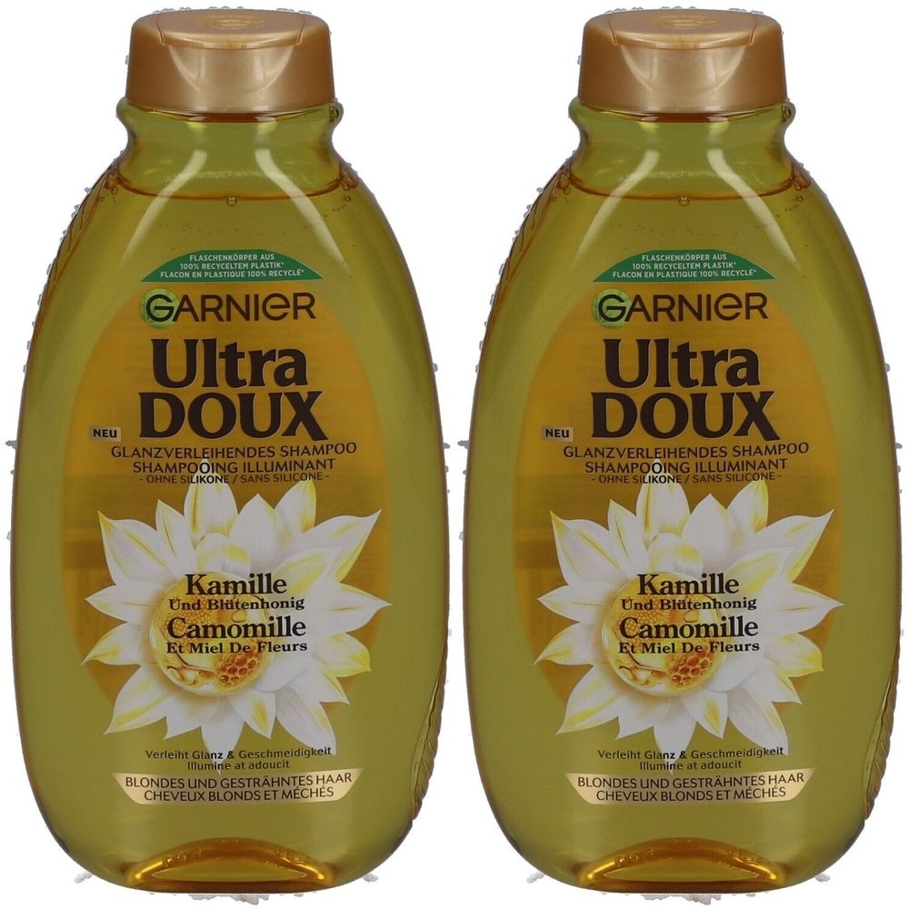 Twee flessen Garnier Ultra Doux shampoo. Gouden dop, gelige vloeistof. Opschrift: Kamille en bloemenhoning. Voor blond haar.