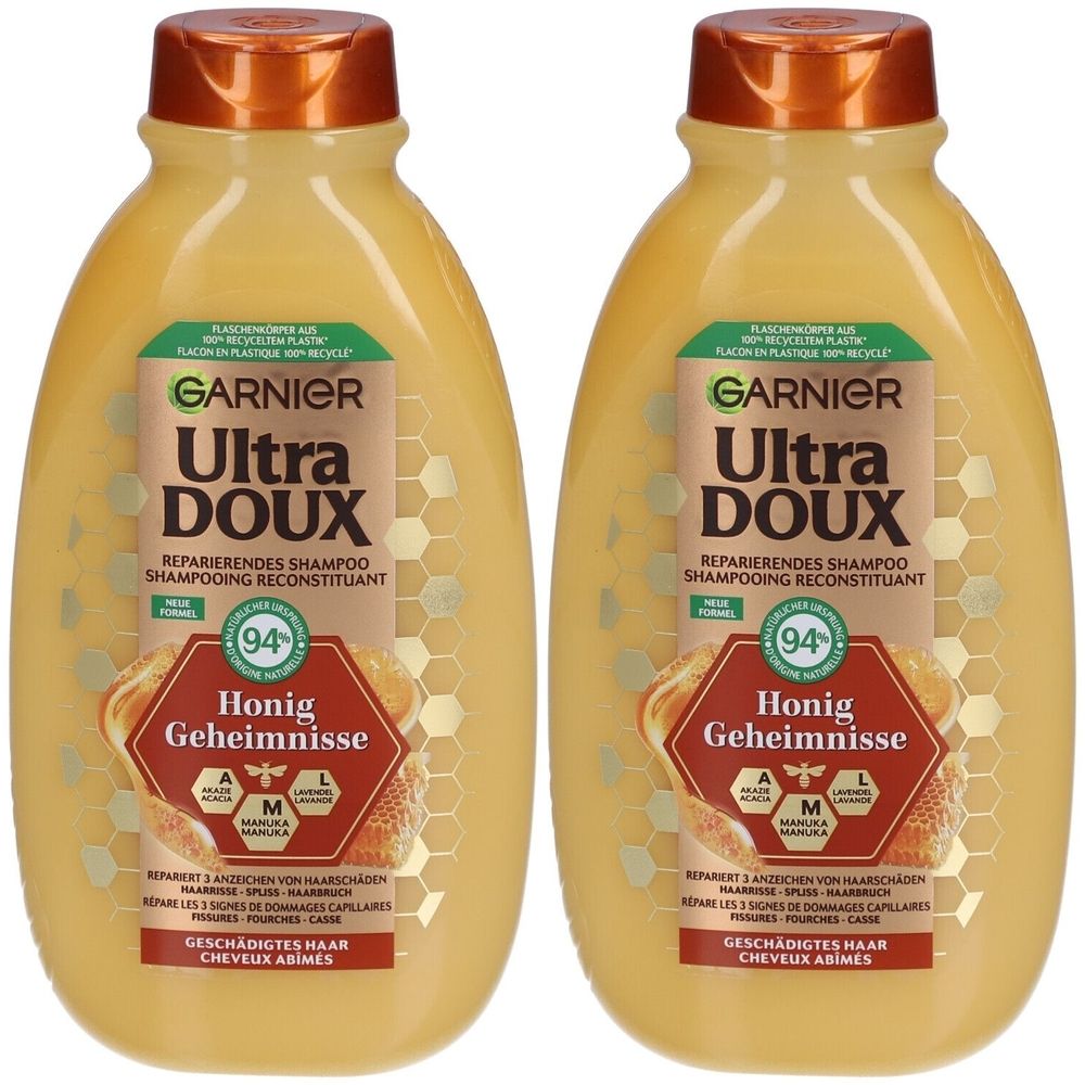 Twee flessen Garnier Ultra Doux Reparierende Shampoo Honig Geheimnisse. Gele vloeistof, bruine dop, etiket met tekst en logo.