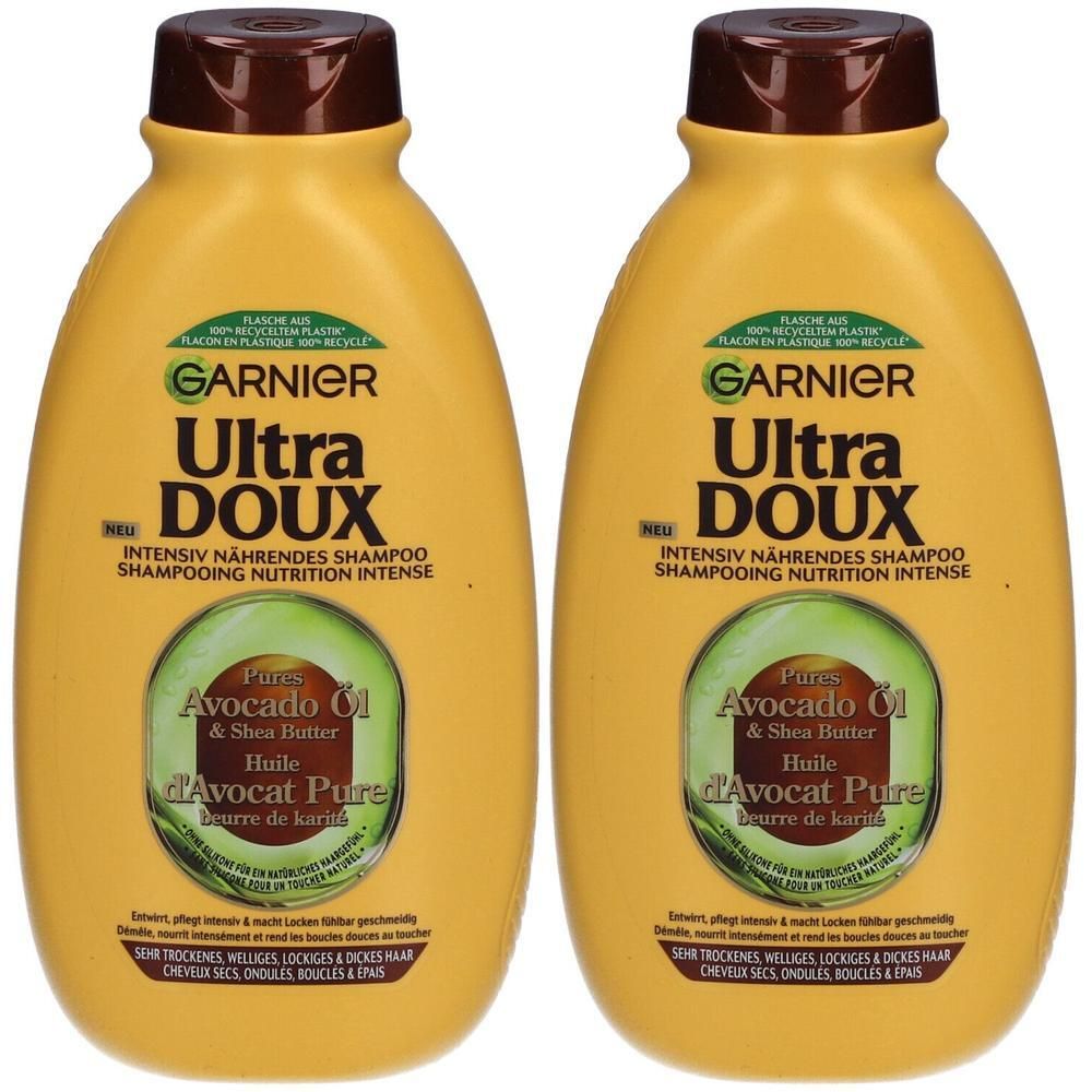 Twee gele flessen Garnier Ultra Doux shampoo met avocado-olie en shea butter. Bruine dop, groene etiketten.
